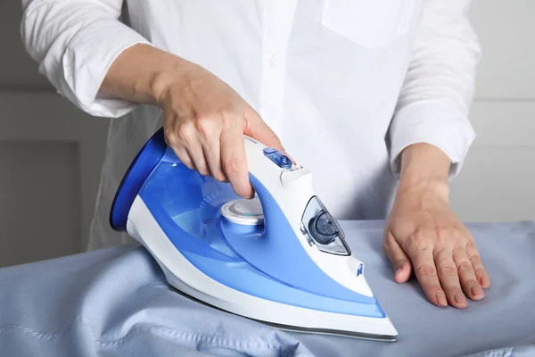 Woman ironing clean shirt on board, closeup