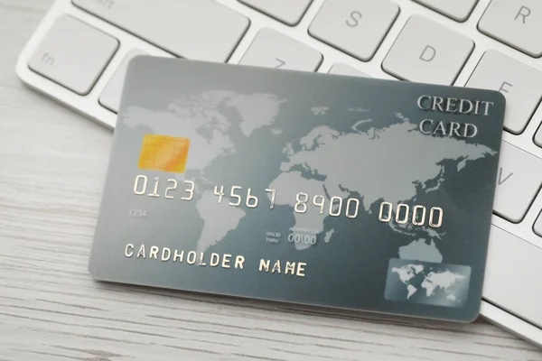 Online payment concept. Bank card and computer keyboard on white wooden table, closeup