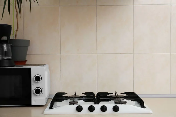 Modern gas cooktop and microwave oven in kitchen, space for text