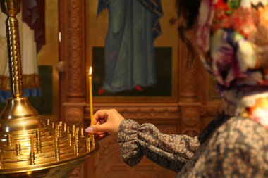 Mature woman putting candle on stand in church, closeup