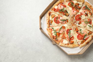 Açık gri masada kutuda nefis deniz ürünleri pizzası, üst manzara. Metin için boşluk