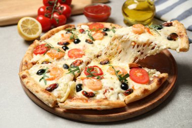 Gri masadaki deniz mahsullü peynirli pizzayı yakın plan çekiyoruz.