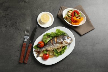 Koyu gri masada limonlu leziz kızarmış balık.