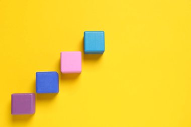 Many colorful cubes on yellow background, flat lay and space for text. Management concept