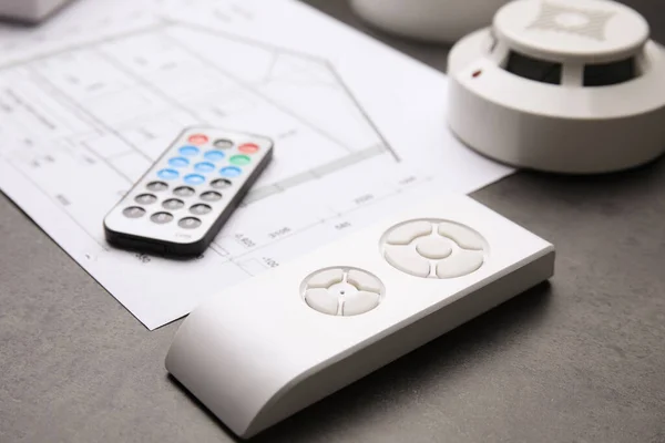 Remote Controls Smoke Detector Building Plan Grey Table Closeup Home — Stockfoto