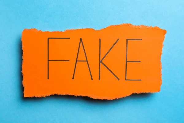 Orange Paper Piece Word Fake Light Blue Background Top View — Stockfoto