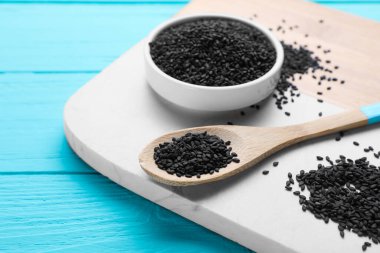 White marble board with black sesame on turquoise wooden table, closeup