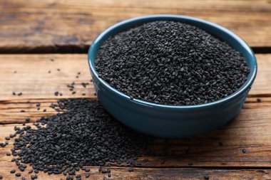 Bowl and black sesame seeds on wooden table