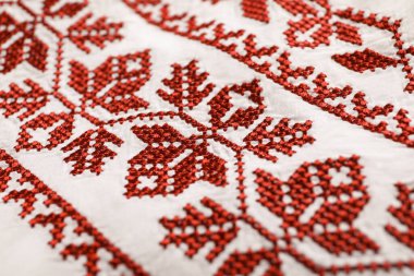 Beautiful red Ukrainian national embroidery on white fabric, closeup