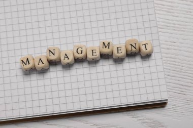 Word Management made of cubes and notebook on white wooden table, top view
