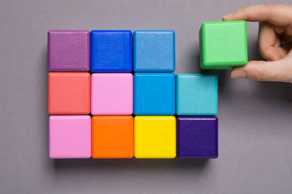 Woman Holding Wooden Cube Others Grey Background Top View Management — 스톡 사진