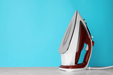 Açık mavi arka planda modern bir ütü, metin için boşluk. Ev aletleri