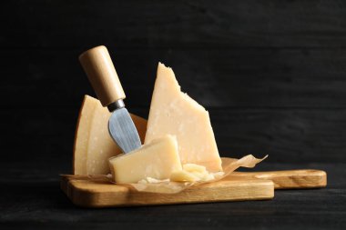 Parmesan peyniri ve bıçak parçaları siyah ahşap masada.
