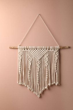 Stylish white macrame hanging on pink wall