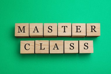 Wooden cubes with words Master Class on green background, flat lay