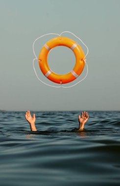 Drowning man with raised hands getting lifebelt in sea