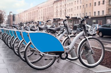 Many bicycles parked outdoors. Bike rental service
