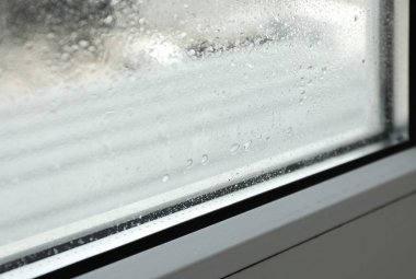 Window glass with drops of condensate indoors, closeup