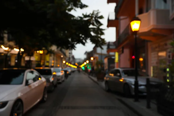Blurred view of city street with parked cars in evening