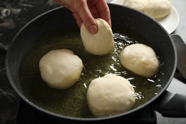 Woman cooking delicious donuts in oil, closeup