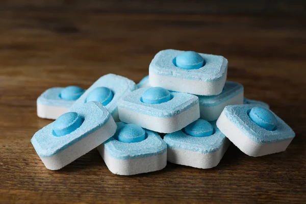 Pile of water softener tablets on wooden table, closeup