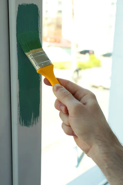 Man painting window frame at home, closeup