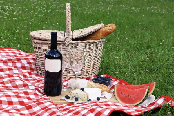 Picnic blanket with delicious food and wine outdoors on summer day