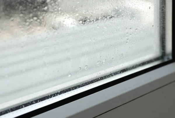 Window glass with drops of condensate indoors, closeup