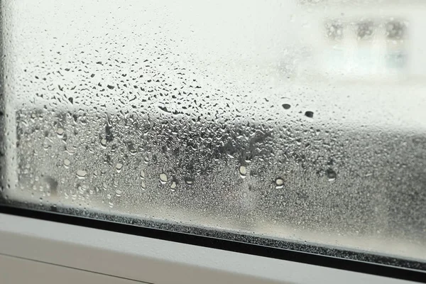 Window glass with drops of condensate indoors, closeup