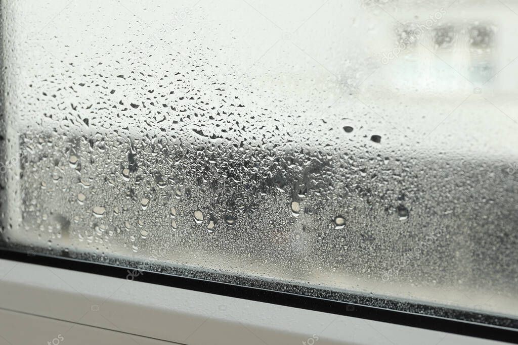 Window glass with drops of condensate indoors, closeup