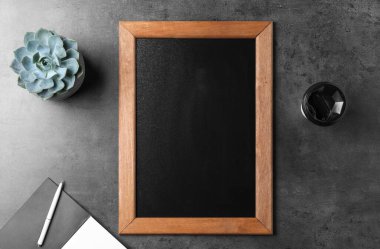 Clean small chalkboard, coffee and plant on grey table, flat lay