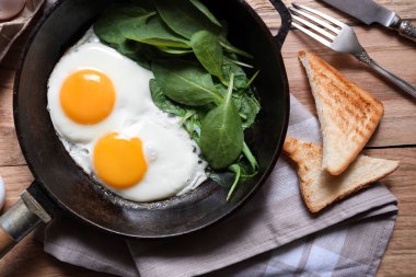 Tahta masada servis edilen ıspanaklı leziz sahanda yumurta.