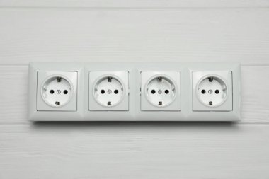 Modern plastic power socket on white wooden table, top view