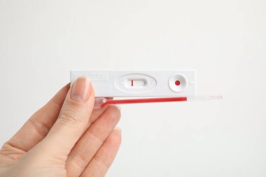 Woman holding disposable express test for hepatitis and pipette with blood on white background, closeup