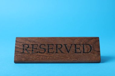 Elegant wooden sign Reserved on light blue background