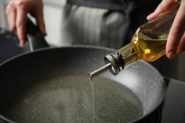 Şişeden tavaya yemek yağı döken kadın, yakın plan.