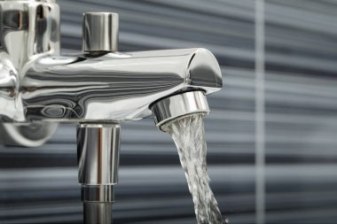 Water flowing from bath tap on blurred background, closeup