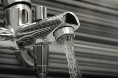 Bulanık arkaplanda banyo musluğundan akan su, yakın plan