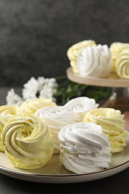 Plate with delicious zephyrs on grey table. Space for text