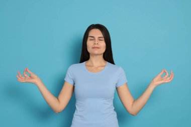 Young woman meditating on light blue background. Zen concept