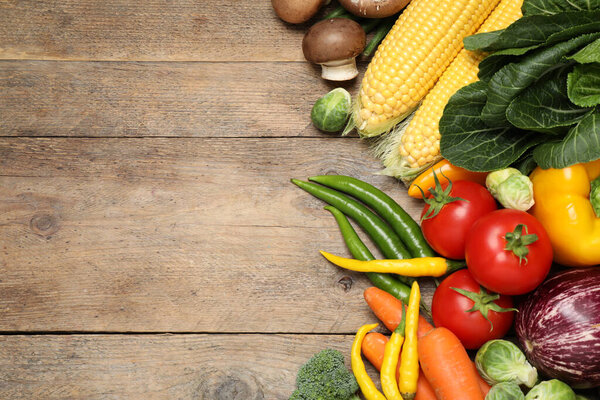 Different fresh vegetables on wooden table, flat lay. Space for text