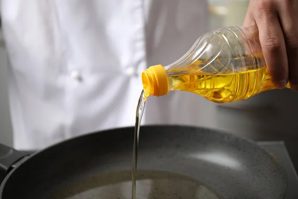 Man pouring cooking oil from bottle into frying pan, closeup