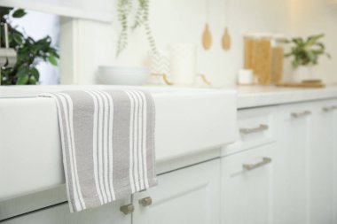 Clean towel hanging on white sink in kitchen