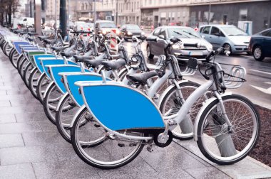 Many bicycles parked outdoors. Bike rental service