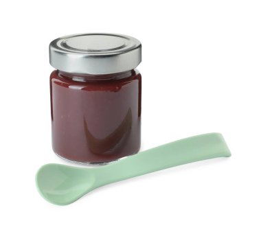 Beyaz arka planda bir kavanoz sağlıklı bebek maması ve kaşık.