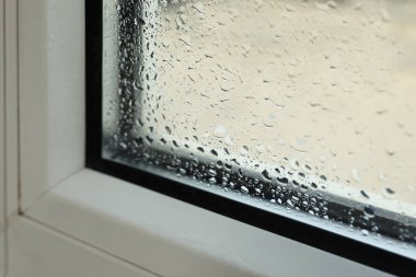 Window glass with drops of condensate indoors, closeup