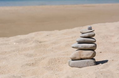 Stack of stones on beautiful sandy beach, space for text