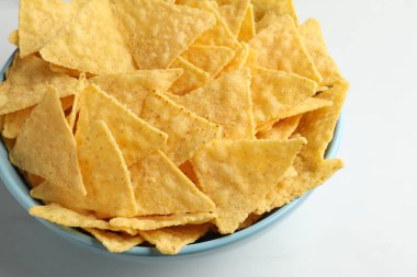 Tortilla chips (nachos) in bowl on white table, closeup
