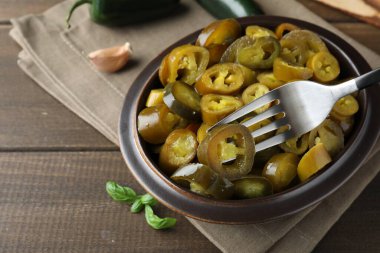 Tahta masadaki çatalla turşulu yeşil biber dilimini alıyorum.