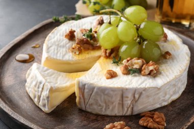 Brie cheese served with grapes, walnuts and honey on grey table, closeup